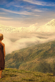 A young Buddhist monk standing on the mountains in nature, with a bird on his shoulder