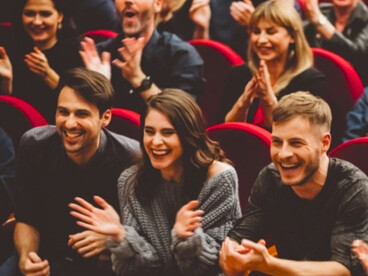 An audience laughing during a live performance, as they would during comedy Slugs
