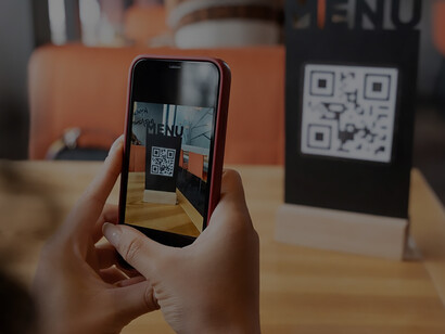 Close-up of hands holding a phone while scanning a digital menu