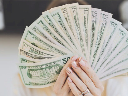 A lady confidently grasping a substantial stack of money
