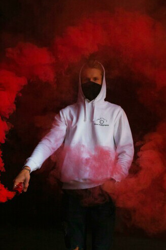 A man wearing a hoodie and mask holds a smoke bomb in Tallinn, Harju County, Estonia