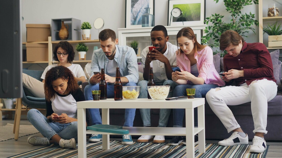 Juntos no mesmo espaço, mas cada um voltado para a própria tela, as pessoas da imagem traduzem o paradoxo das redes sociais: a promessa de conexão pode coexistir com o afastamento das relações presenciais. A conexão virtual nem sempre impede que a distância se instale entre aqueles que estão lado a lado