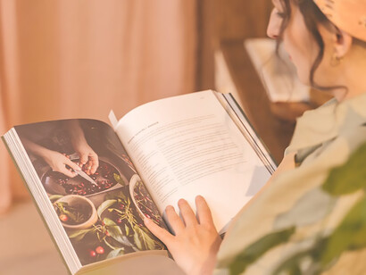 In this captivating scene, a woman skillfully uses a cookbook to guide her cooking endeavors in the kitchen, illustrating the timeless joy and expertise of home cooking