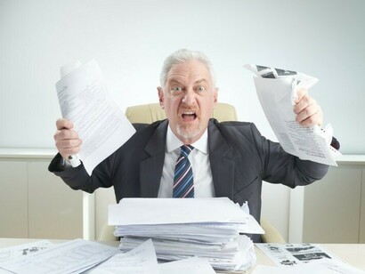 Senior manager overwhelmed by paperwork, highlighting bureaucracy at a lawmaker’s desk