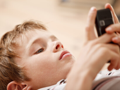 La era digital. Un niño chatea con su teléfono móvil