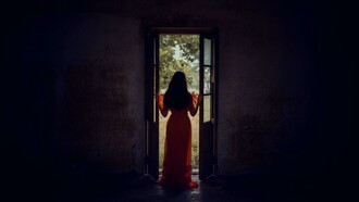 Standing at the threshold between darkness and light, she pauses in the stillness of becoming