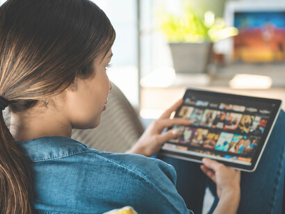 Woman browsing a streaming platform on her tablet, choosing a movie for a relaxing evening of entertainment at home