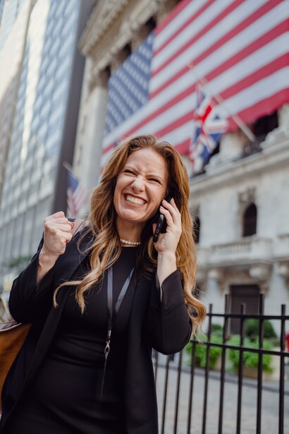 A woman cheering at her winning battle, in the business world, on the phone with a work colleague
