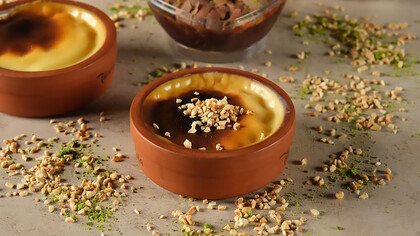 Indulge in delectable rice pudding served in a traditional clay bowl, adorned with crunchy hazelnut pieces