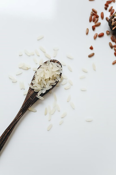 Arranging rice grains in wooden spoons, set against a clean white background for a visually appealing composition
