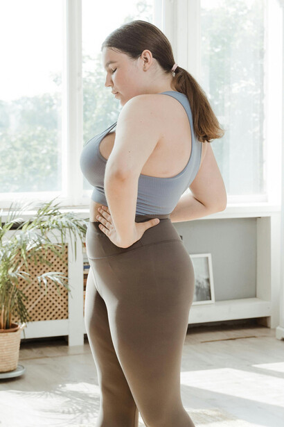 A woman wearing brown leggings holding a dumbbell during a workout
