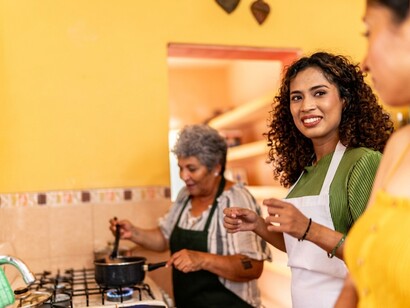 A young woman cooking a traditional family recipe with her grandmother in their home kitchen