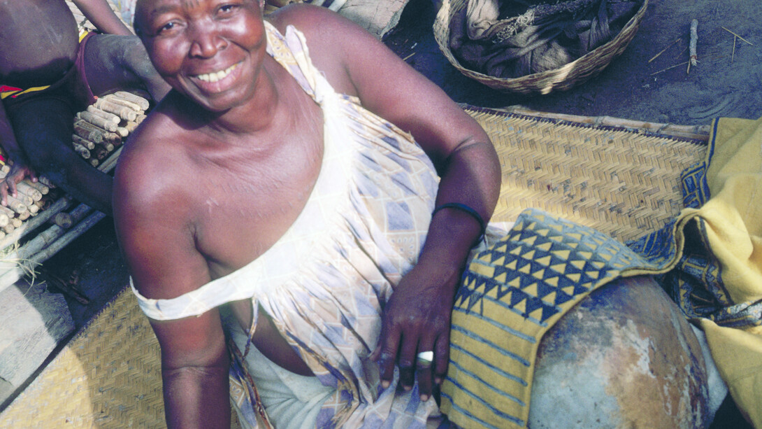 Ill. 1. Tonguoy Diarra pausing during the painting of the sleeve of a man’s tunic. The sleeve bearing the “Piece of a gourd” (Filen koloni) pattern is stretched across an empty calabash. Dyers always use the calabash as a support because it enables them to hold the metal spatula vertical to the cloth and to work on very small areas without staining other sections of the design. Kolokani.  
Photocredit Sarah C. Brett–Smith  
