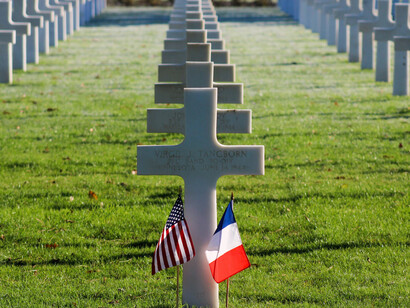 Graves of fallen soldiers with the cross symbol for their headstones, with the American and French flag