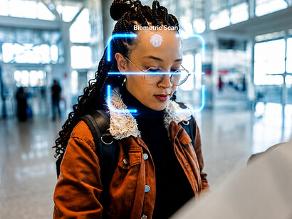 Young woman completing biometric facial recognition at an airport self-service checkpoint