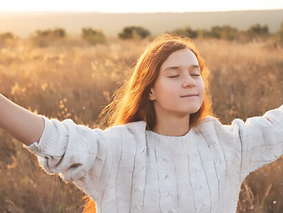 Captured in a desolate terrain, a woman's prayer gesture symbolizes selflessness and grace