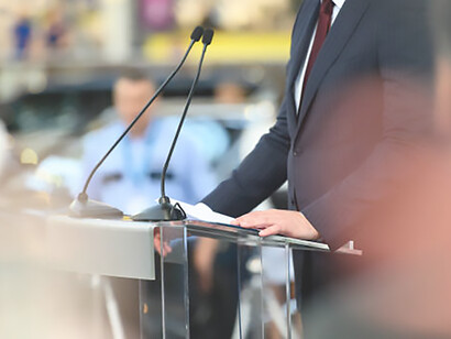 The political figure passionately articulates their views, captivating the audience from behind the lectern