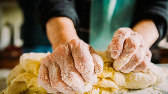 Close-up of an elderly Italian woman’s hands making fresh pasta by hand
