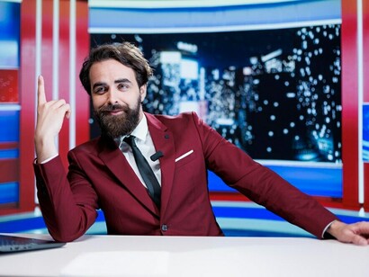 The host of a late-night show airs fresh newsroom footage and provides updates on global current affairs, with a media correspondent reporting the latest news on a worldwide TV program