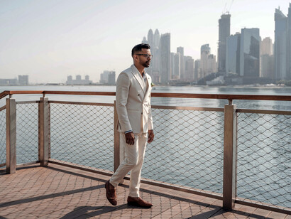 Dubai, United Arab Emirates. A man wearing a white suit walks beside a fence
