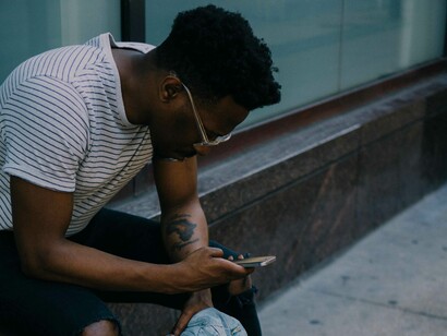 A man sitting on a building's edge checking his social media notifications is clearly a sign he's addicted