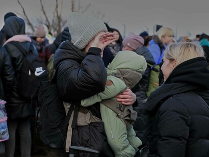 A woman holds her baby, wiping her eyes of tears; A scene from the Palanca-Maiaki-Udobnoe border crossing point, between the Republic of Moldova and Ukraine on 4 March 2022. Photos from the UN Women