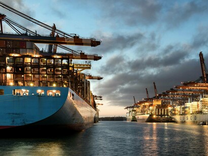 A busy harbour illuminated at twilight, symbolising the backbone of economic globalisation