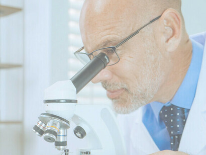Dentro del laboratorio, un científico está inmerso en su trabajo, utilizando un microscopio para realizar investigaciones meticulosas y contribuir a los avances científicos.