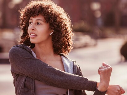Mulher se alonga enquanto ouve música. A música não só energiza o corpo, mas também rejuvenesce a mente, tornando-se uma ferramenta valiosa para combater a apatia e a desmotivação