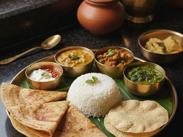 A wholesome and traditional Brahmin meal, beautifully arranged on a brass thali. This spread features soft rotis, fragrant white rice, a vibrant spinach curry, a potato and pea curry, and cooling raita, all reflecting the pure and balanced flavors of South Indian vegetarian cuisine