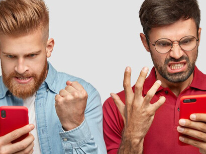 Two frustrated individuals glaring at their smartphone screens, depicting the adverse effects of social media engagement