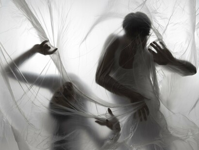 Two blurred forms gliding behind a thin curtain, representing how fear lurks just beyond perception