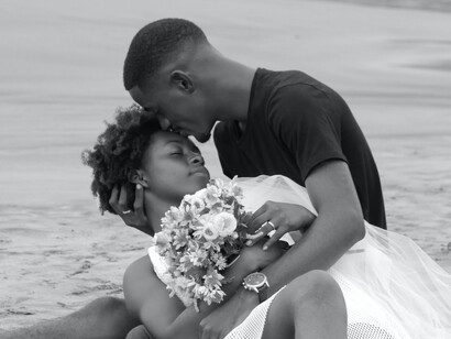 A husband lovingly holds his new bride on the beach