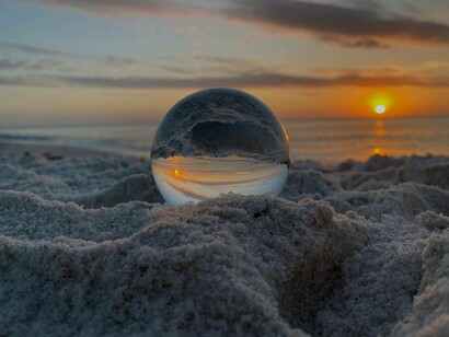 Palla di vetro sulla sabbia al tramonto
