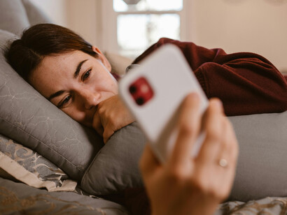 A woman lying in bed holds her phone close, sharing an emotional late-night call with her long distance boyfriend