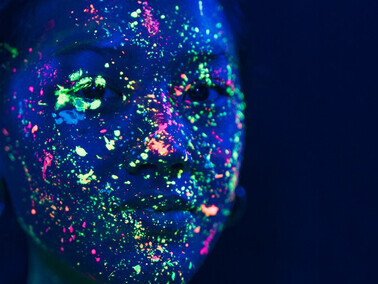 Close-up portrait of a woman with vibrant fluorescent makeup, evoking abstract colors and emotions