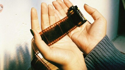 Mani attente e delicate avvolgono la pellicola cinematografica, come a proteggere storie, ricordi e sogni racchiusi in ogni fotogramma