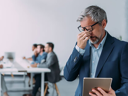 A businessman overwhelmed by economic pressures during an office meeting amid a recession