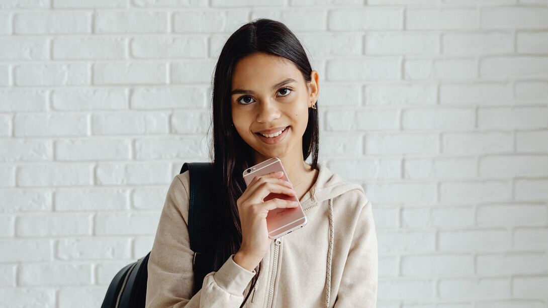 Aluna adolescente segura celular dentro da escola