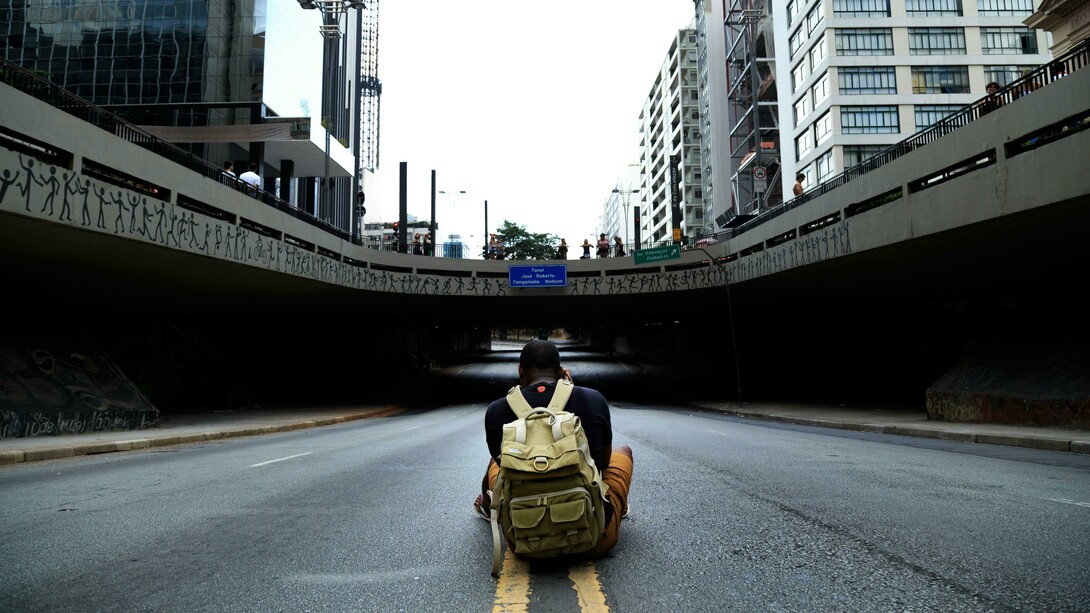 Homem fotografa placa que dá nome a um túnel. Será que alguma pessoa tem mérito suficiente para ser nome de rua? Muitos feitos heroicos ou significativos se dissipam com o tempo, ficam ultrapassados e, até mesmo, o que foi muito importante e valioso numa ocasião, em outra época pode ser irrelevante
