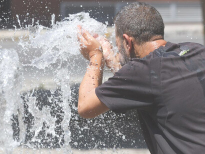 Hombre intenta refrescarse en una fuente durante ola de calor en España, 2023