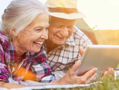 Una coppia di perennials stesi sul prato mentre consultano un tablet  