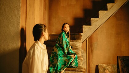 Woman in a green outfit standing on stone stairs 