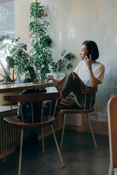 In a cozy café, a woman wearing a white shirt sits by herself while making a phone call