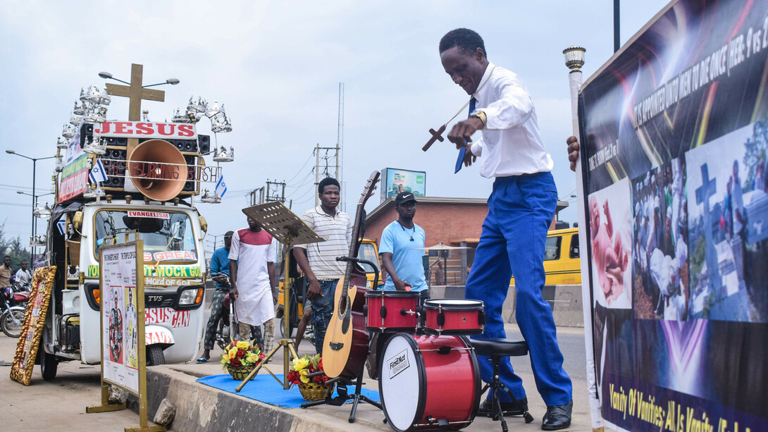Predicador, calle, instrumento musical y pancartas en Nigeria