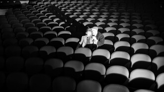 Black-and-white image of a couple seated in an empty theater