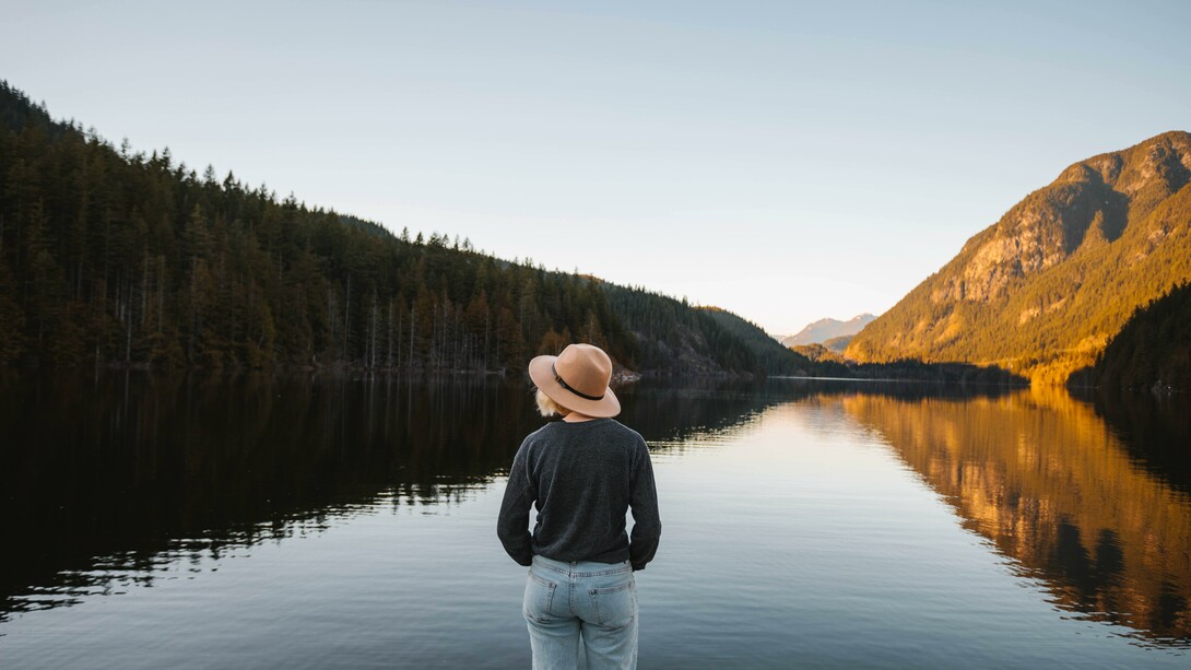 Person connecting with nature by standing in front of a lake to find a mental peace