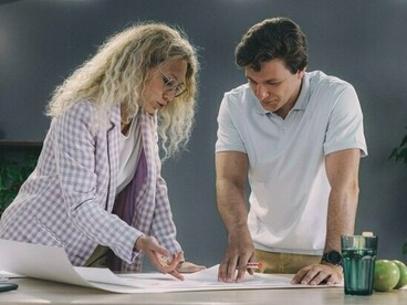 Professionals refining a project blueprint together, symbolizing that strategy gains value only through action