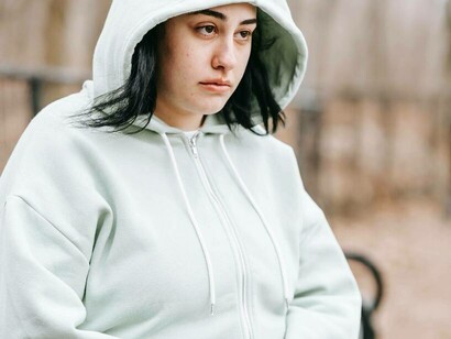 A woman who is an introvert is sitting on a bench alone in a park