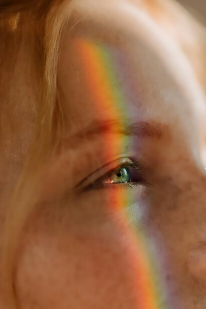 Image of a pretty woman with a rainbow hovering over her eyes on the right side of her face